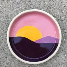 a purple and yellow plate with mountains painted on it