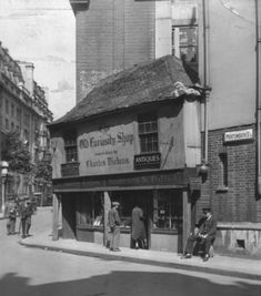 an old black and white photo of people standing in front of a building on a street corner