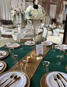 the table is set with gold and white plates, silverware, and centerpieces