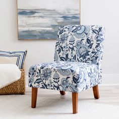 a blue and white chair sitting in a living room next to a painting on the wall