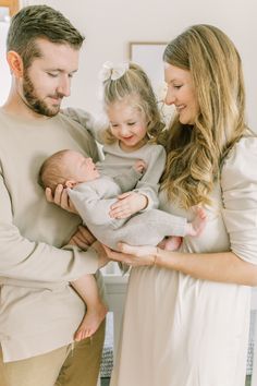 a man and woman holding a baby in their arms