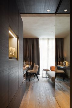 a room with wooden floors and curtains on the windowsills is lit by recessed lights