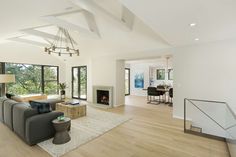 a large living room with white walls and wood flooring on the side, along with modern furniture