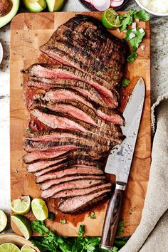 sliced steak on cutting board with limes and onions