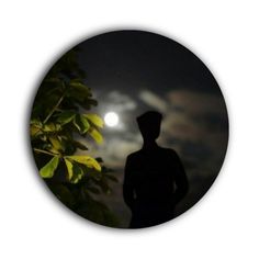 the silhouette of a man standing in front of a full moon at night with trees