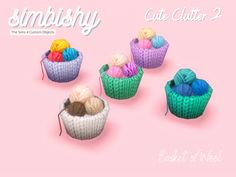 there are four knitted cupcakes with balls of yarn in them on a pink background