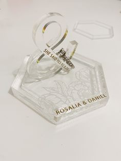 two wedding rings sitting on top of a glass block that says roslia & danielle