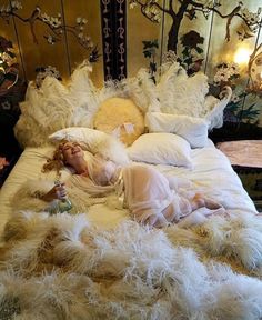 a woman laying on top of a bed covered in white feathers