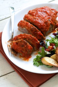 a white plate topped with meat covered in marinara sauce next to potato wedges