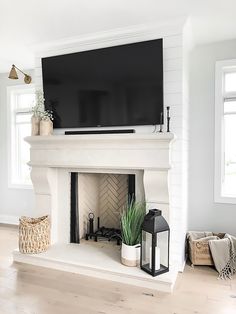 a white fireplace with a flat screen tv above it and some plants on the mantle