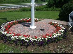 a fire hydrant surrounded by flowers in the middle of a garden with a brick walkway