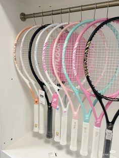 tennis rackets are lined up in a row on the wall behind a white shelf