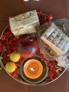 an assortment of food is arranged on a plate with a candle and some fruit in the middle