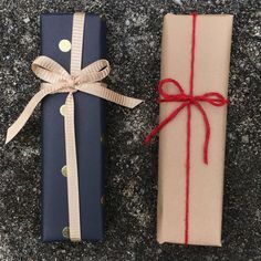 two wrapped presents sitting on top of a stone floor next to each other and tied with red string