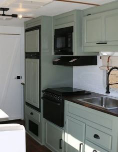 a kitchen with green cabinets and black appliances