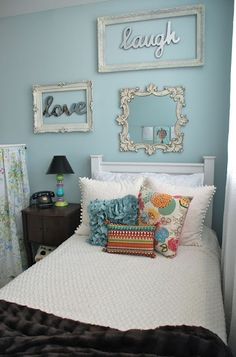 a bedroom with blue walls and pictures on the wall above the bed, along with decorative pillows