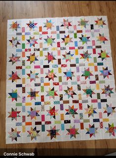 a quilt made with different colored blocks on top of a wooden floor next to a table