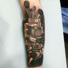 a black and white photo of a tattoo on the arm with makeup brushes in it