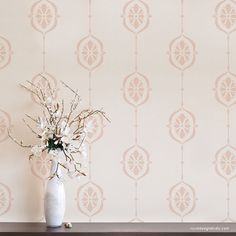 a vase filled with flowers sitting on top of a wooden table next to a wall