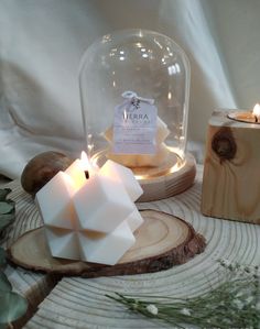 two candles sitting next to each other in front of a glass dome filled with white cubes