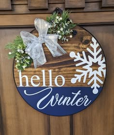 a wooden sign that says hello winter with snowflakes and greenery on it