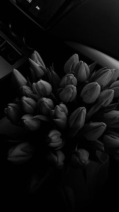 black and white photograph of flowers in front of a car dashboard with the dash light on