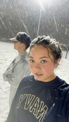 a woman standing in the snow with a man behind her