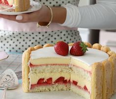 a woman is holding a piece of cake with strawberries on top and the rest of the cake has been cut