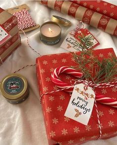 presents wrapped in red and gold wrapping paper on a white tablecloth with christmas decorations