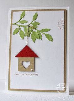 a handmade card with a birdhouse and heart hanging from the tree on it's side