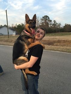 a man is hugging his dog on the street