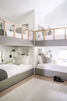 two bunk beds in a room with white walls and wood flooring, along with rugs on the floor