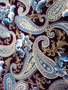 close up view of the blue and gold paisley pattern on this purple shirting material