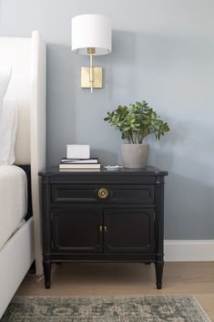 a nightstand with a potted plant next to it on top of a carpeted floor