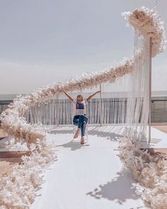 a woman standing on top of a snow covered ground next to an arch made of white yarn