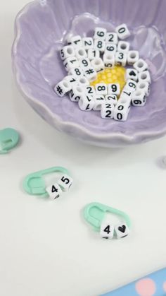 a purple flower shaped bowl with numbers on it and two clips in front of it