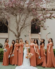 a group of women standing next to each other in front of a tree with flowers