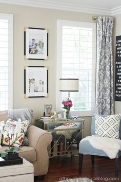 a living room filled with furniture and pictures hanging on the wall above it's windows