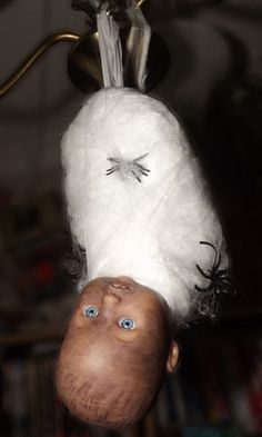 a doll hanging upside down from the ceiling with eyes on it's head and nose