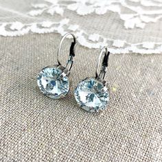 "Heatherly Designs dangling leverback earrings made with a rivoli cut Swarovski crystal set in solid brass lever back earrings plated in your choice of precious metal finish. Shown in a pale icy blue and aged silver. ●Nickel free ●Size (L x W): 7/8\" x 1/2\" or 22 x 12mm ●Swarovski crystal color(s): Light Azore ●Arrives in our signature Heatherly gift box. Handmade with ❤ by Heather ● ● ● ● ● ● ● ● ● ● ● ● ● ● ● ● ● ● ● ● ● ● ● ● ● ● ● ● →Quantity Discounts listed below: 10% off 3-6 pcs - 10OFF3 Gift Box Handmade, Box Handmade, Etsy Bridesmaid Gifts, Earrings Simple, Leverback Earrings, Icy Blue, Crystal Set, Dangling Earrings, Delicate Earrings