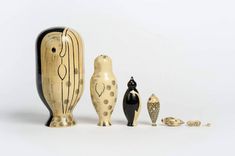 three wooden figurines sitting next to each other on a white surface, one is black and the other is gold