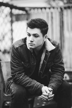 black and white photograph of a young man sitting on a bench looking at the camera