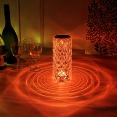 a wine glass sitting on top of a wooden table next to bottles and two glasses