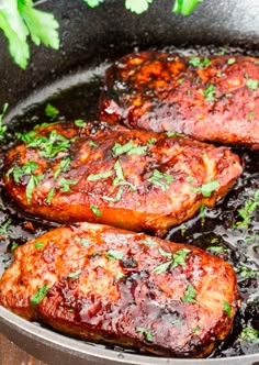 three pieces of meat cooking in a pan with sauce and parsley on the side