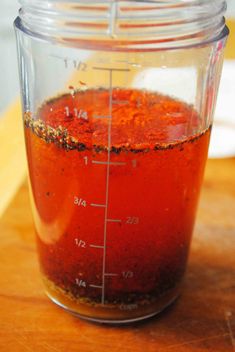 a measuring cup filled with red liquid on top of a wooden table