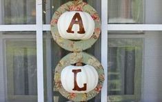 two white pumpkins with letters on them sitting in front of a window