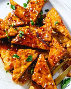 a white plate topped with tofu covered in sauce and garnished with parsley