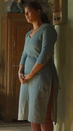 a woman standing in front of a wooden cabinet