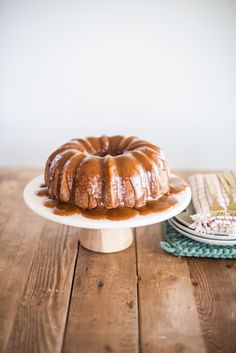 a bundt cake sitting on top of a white plate covered in caramel sauce