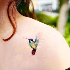 a small hummingbird tattoo on the back of a woman's shoulder